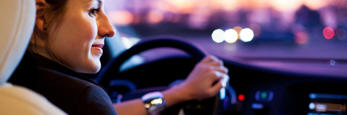 Driving a car at night – pretty, young woman driving her modern